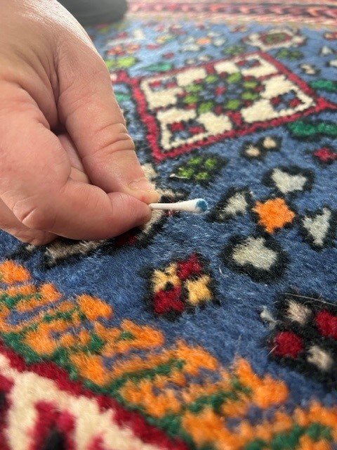 Testing a rug’s colors for dye bleeding with a white cloth