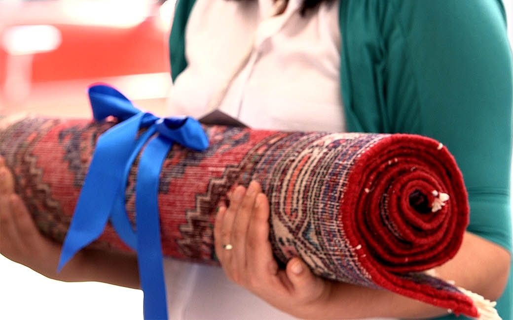 A freshly cleaned rug rolled and tied with a blue ribbon, ready for delivery