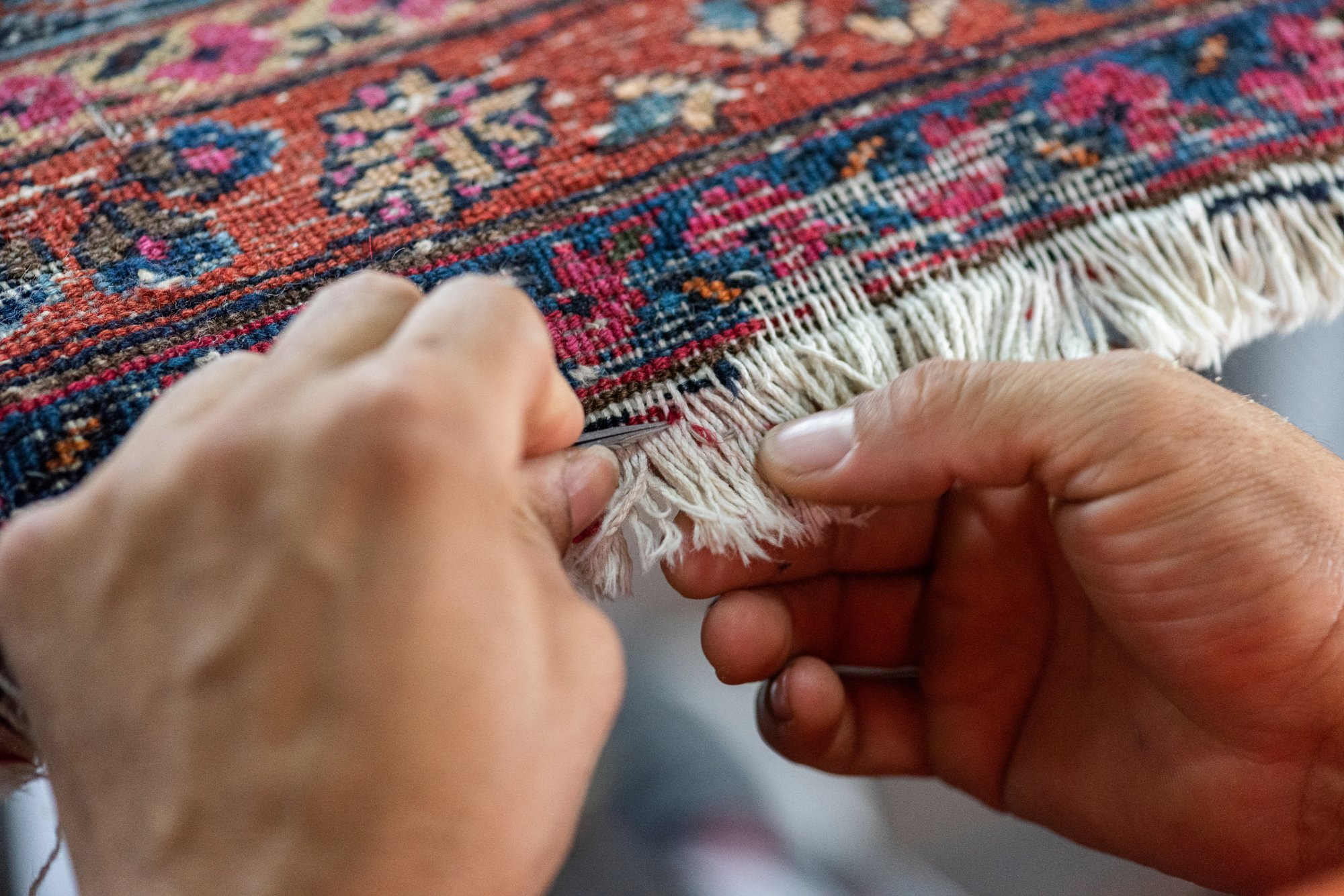 Hands repairing the fringe of an Oriental rug