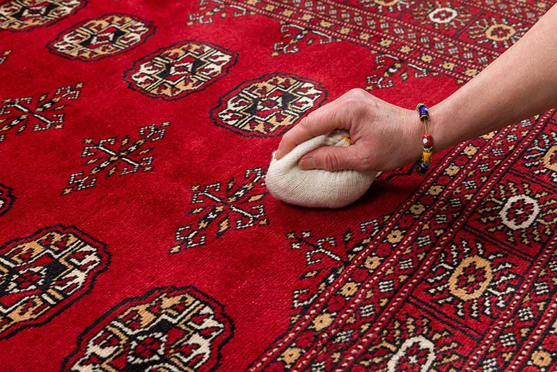 A white cloth blotting a spill on a red Oriental rug